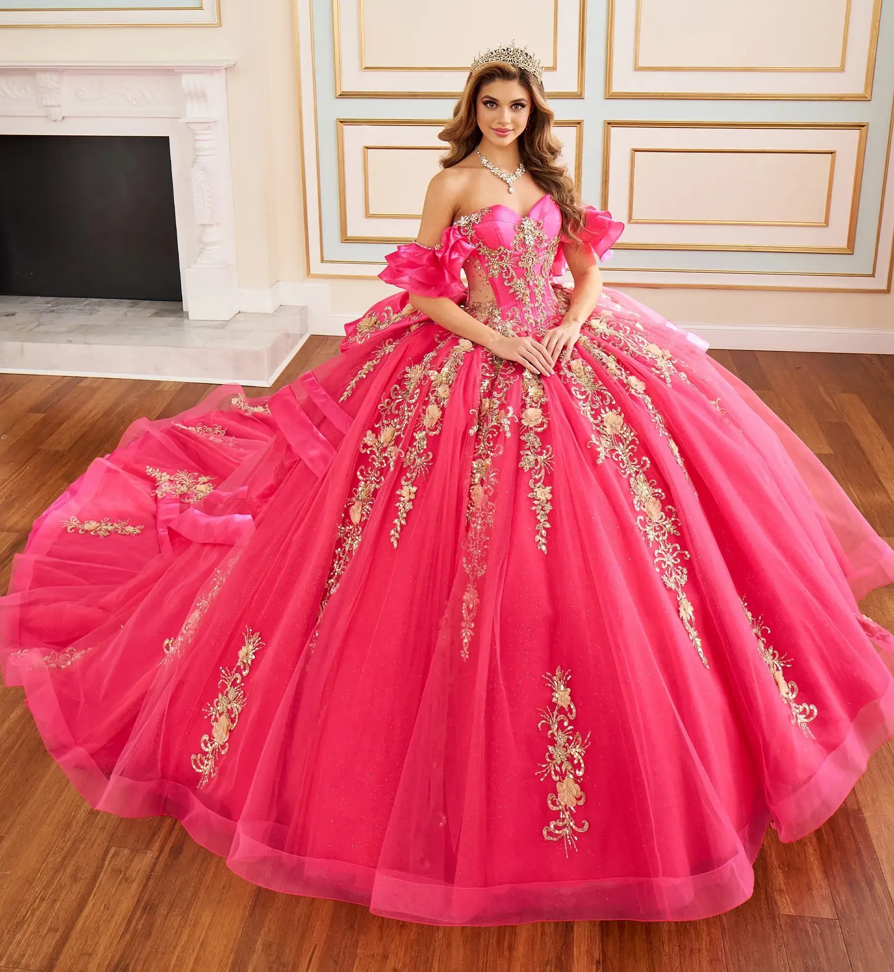 Model is wearing a hot pink and gold quinceanera gown with an off the shoulder neckline