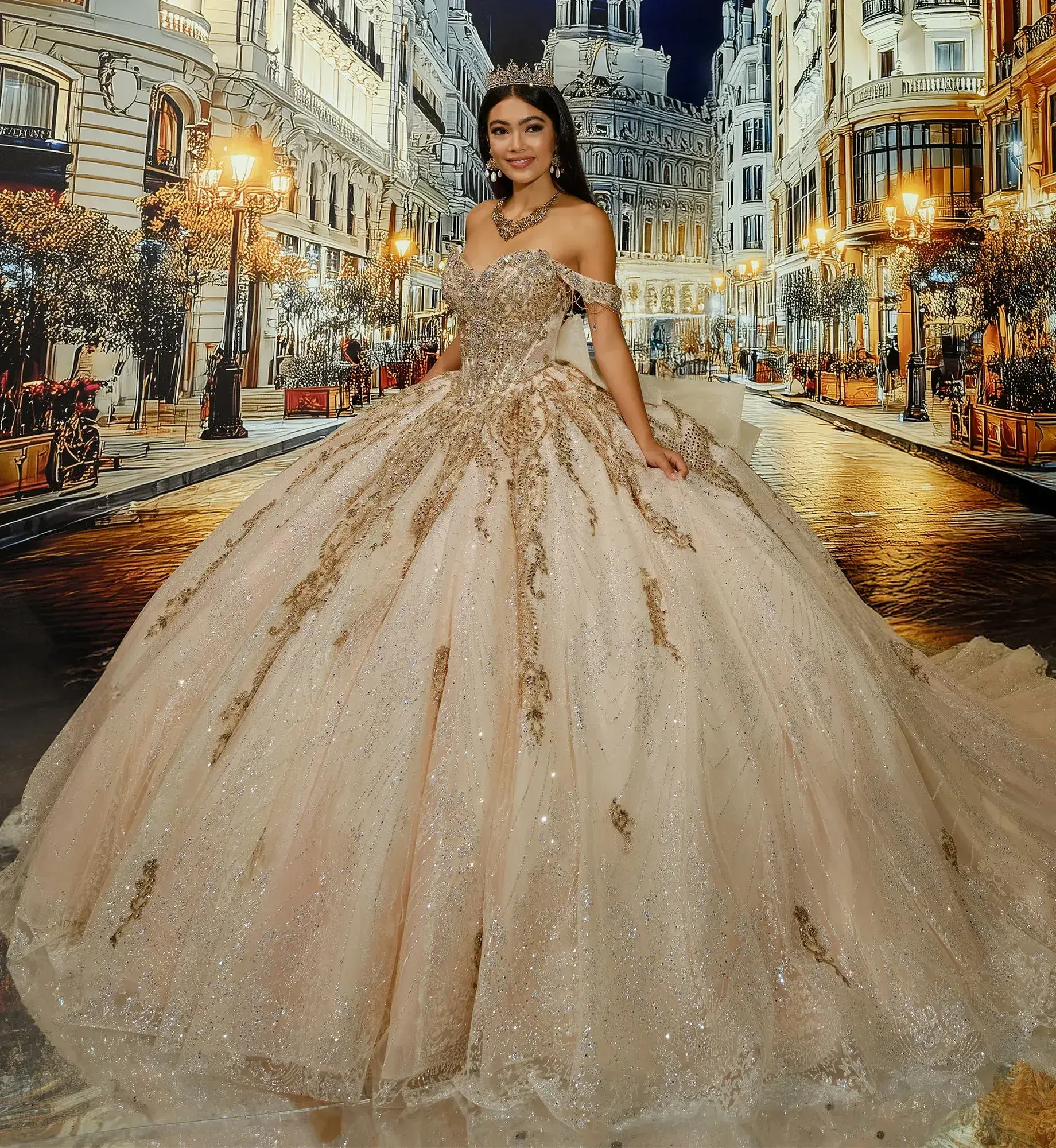 A woman stands elegantly in a lavish, glittery ball gown with gold accents, set against a picturesque, illuminated city street backdrop at night.