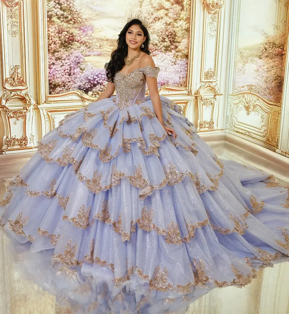 A young woman in a beautiful light purple ball gown with layered ruffles and golden embellishments, standing in an ornate room with floral decorations.