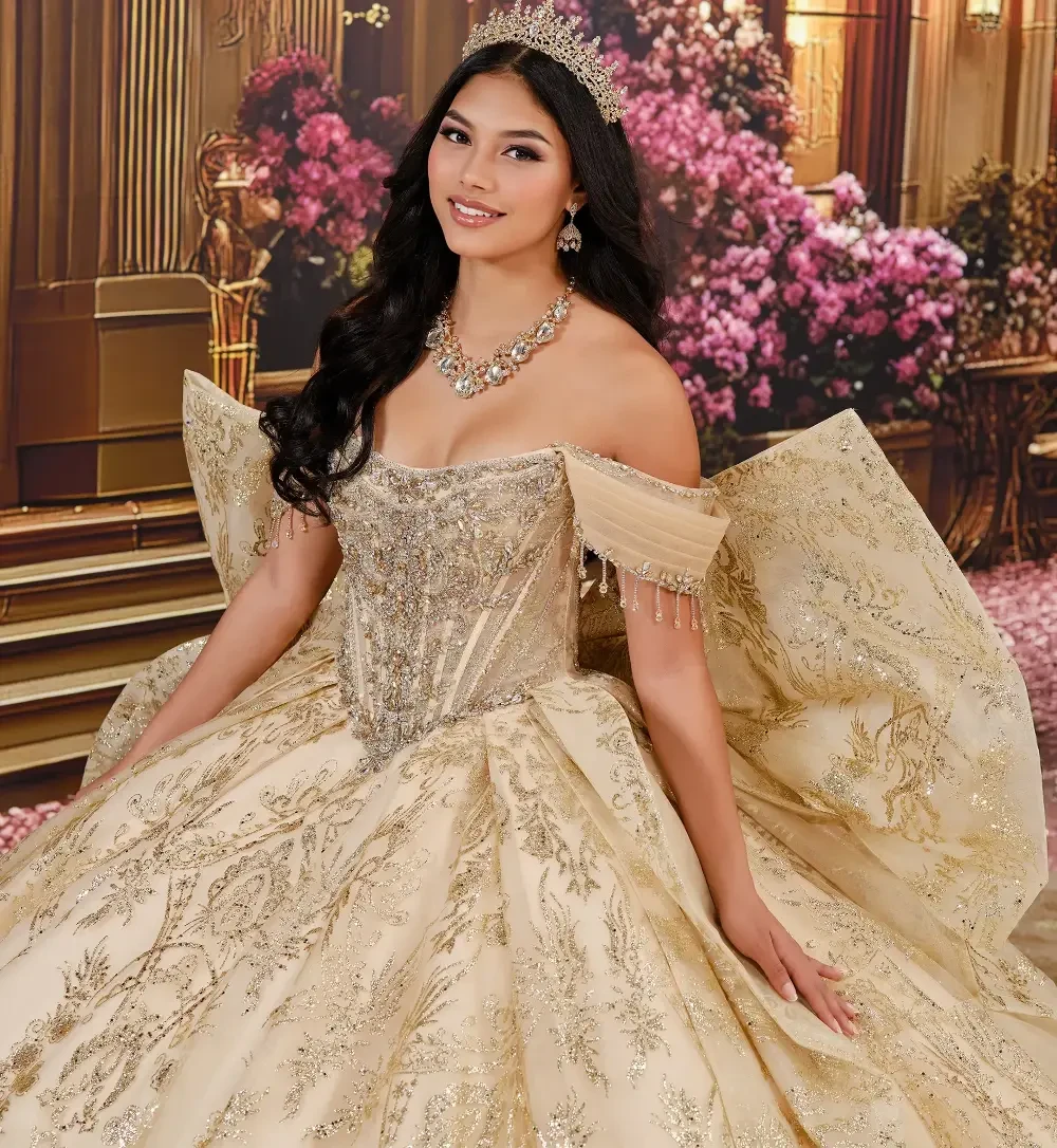 A woman in a luxurious golden ball gown with intricate designs, standing in an ornate setting with flowers and grand architecture in the background.