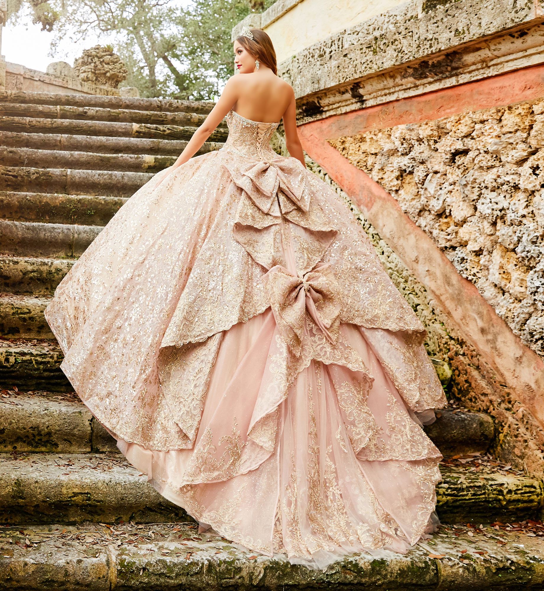 Brunette model in rose gold quinceañera dress with dramatic bows